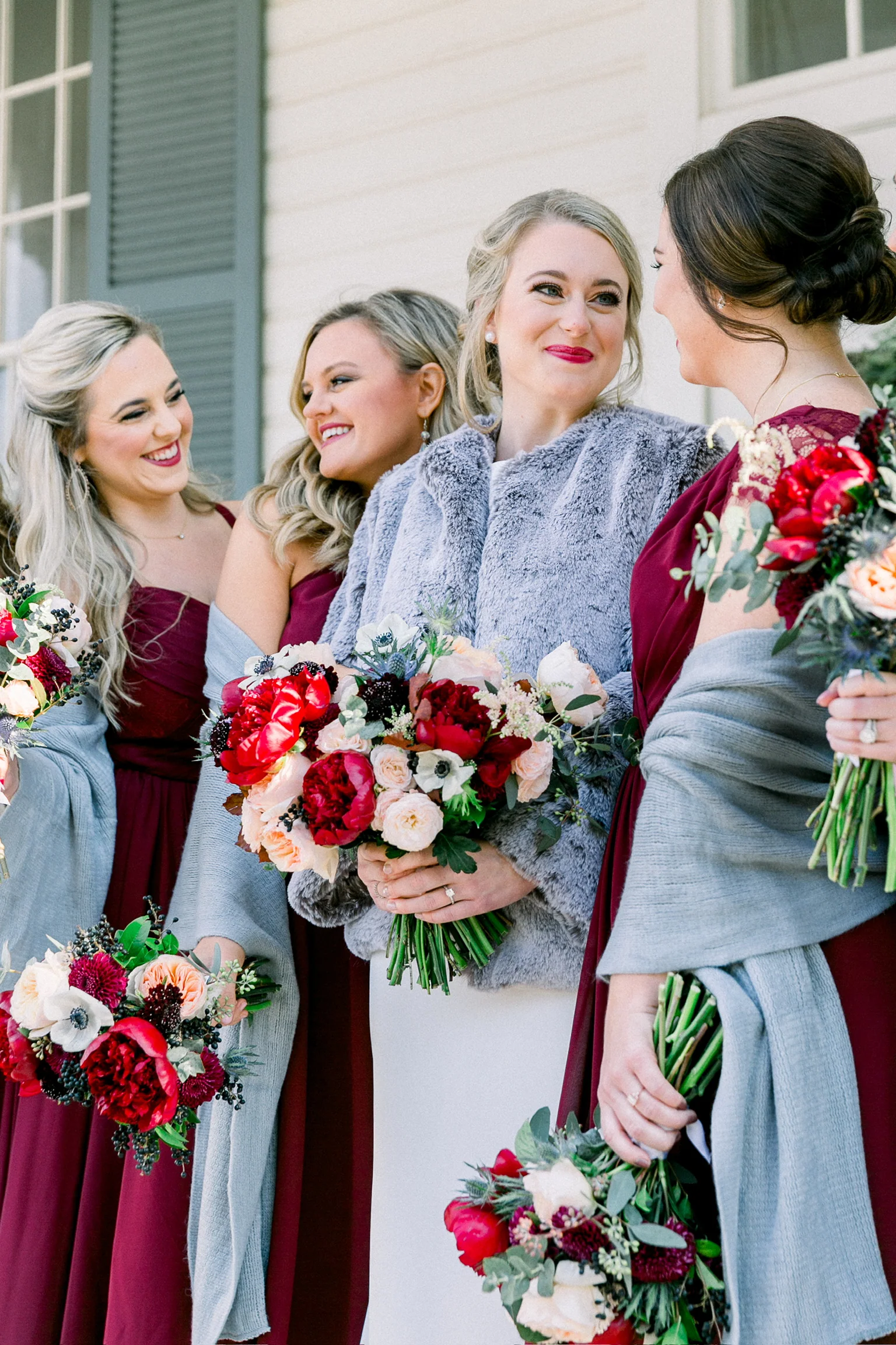 Bride with bridesmaids holding red and ivory bouquets