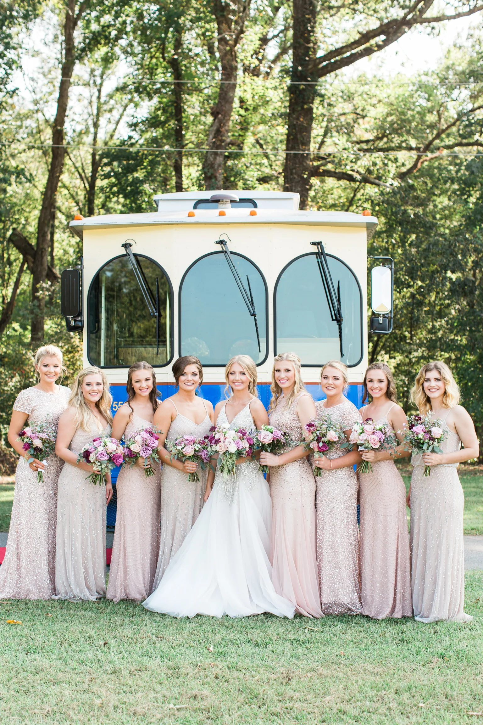 Bride and bridesmaids posed before a vintage trolley
