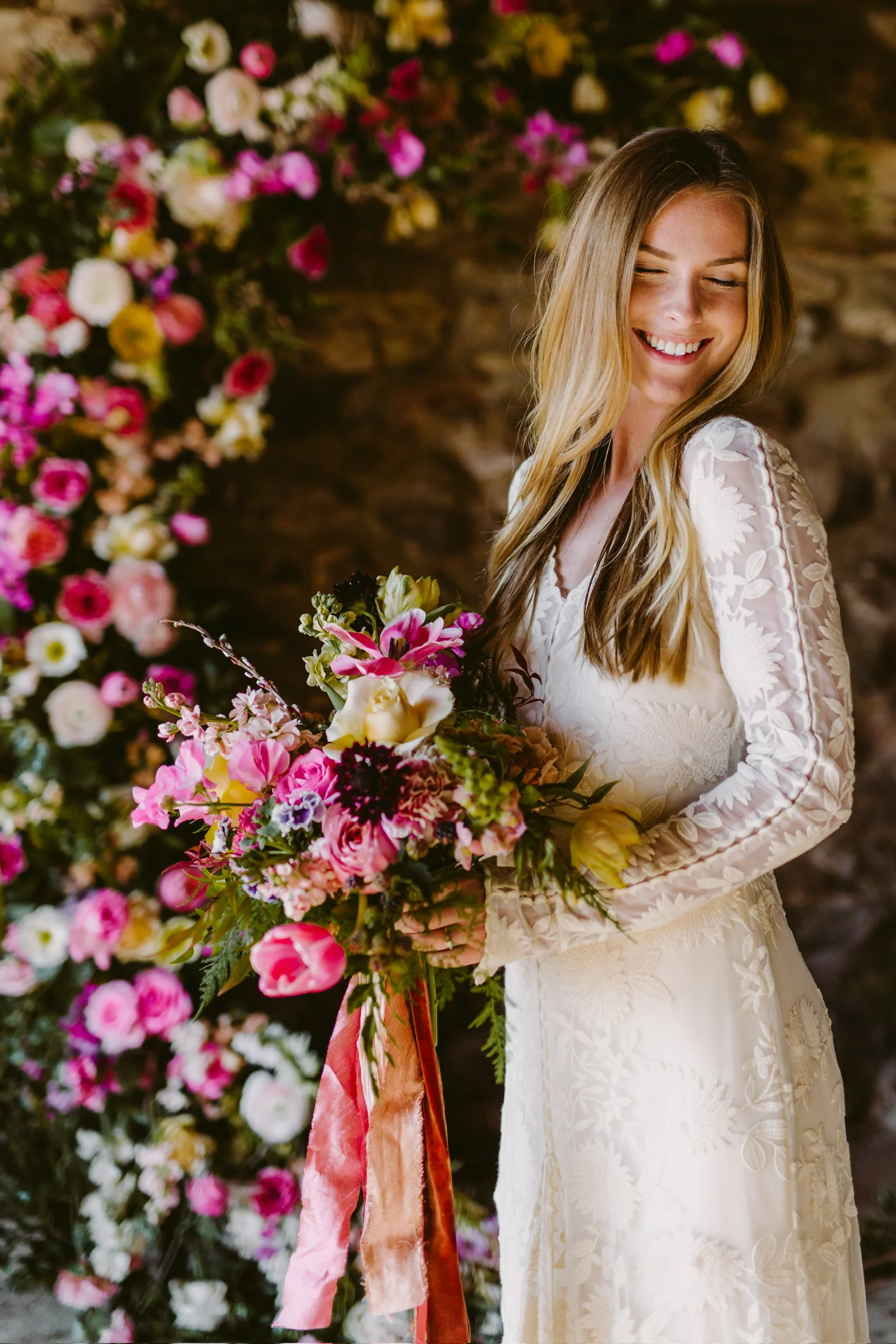 Bride holding a vivid garden-style bouquet before a floral installation