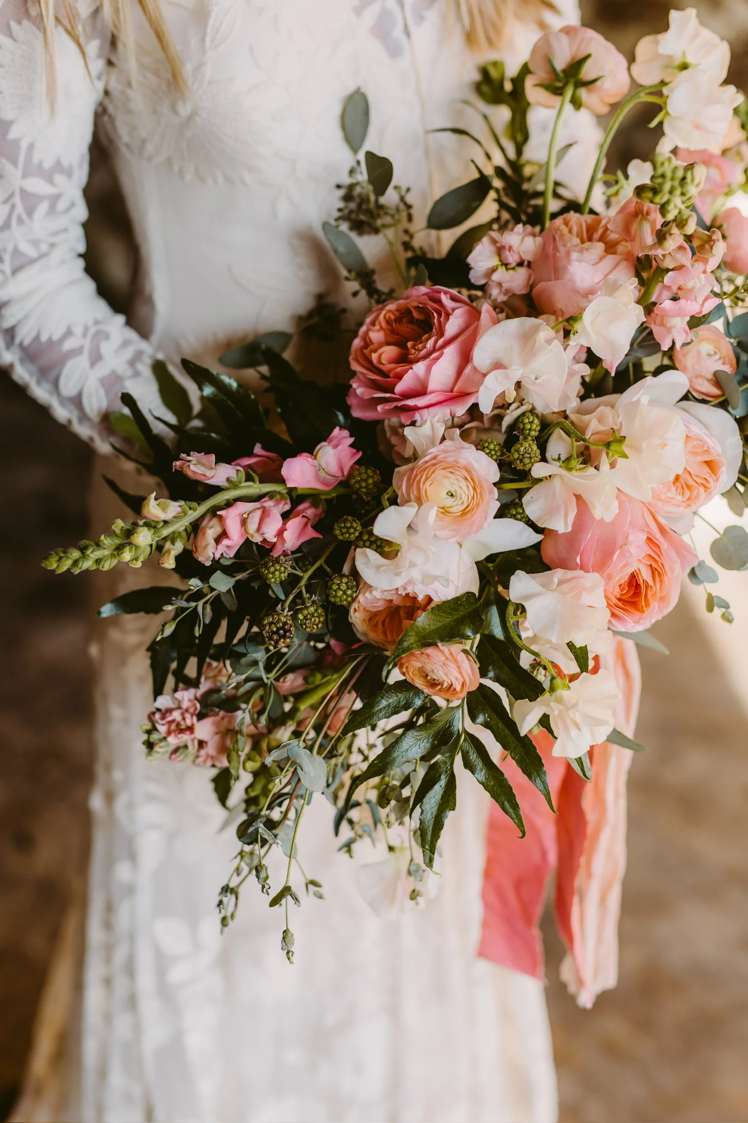 Close view of a blush bridal bouquet against a lace gown